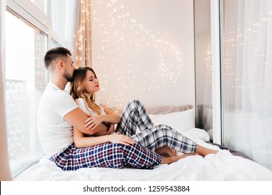 Stunning Girl In Pajama Lazy Posing With Boyfriend. Adorable Young Woman Lying In Bed Near Husband In Weekend.