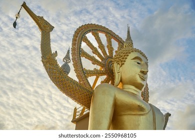 A stunning golden Buddha statue adorned with intricate details and surrounded by a serene sky. Located in Koh Samui, Thailand. - Powered by Shutterstock