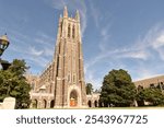 A stunning high Gothic-style building at Duke University, with a towering spire and detailed stonework. The iconic structure stands tall amidst lush greenery, exuding historic elegance.