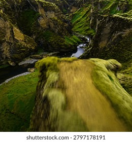 A stunning high-resolution aerial view of a dramatic moss-covered canyon featuring towering rock formations, lush green cliffs, and a winding river flowing through the valley. This breathtaking natural landscape captures the beauty of untouched wilderness, showcasing vibrant textures, rugged terrain, and cinematic scenery ideal for travel, adventure, nature, and environmental projects.