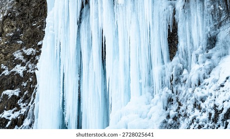 Stunning icefall cascades dramatically from a river cliff in Rudawka Rymanowska, showcasing the beauty of winter's frozen artistry in a natural setting.