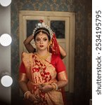 Stunning Indian bride during make up in Hindu traditional wedding clothes Saree and golden jewelry in a make up studio. Bengali wedding. Kolkata wedding. Indian model bridal shoot. Indian wedding.