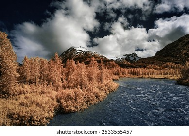 A stunning landscape of a river flowing through a forest with snow-capped mountains in the background under a partly cloudy sky - Powered by Shutterstock