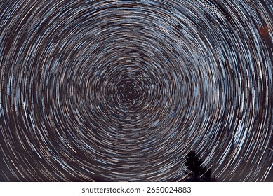 A stunning long-exposure photograph of circular star trails around Polaris, the North Star. This captivating image showcases the apparent rotation of the night sky due to Earth’s rotation, captured ov