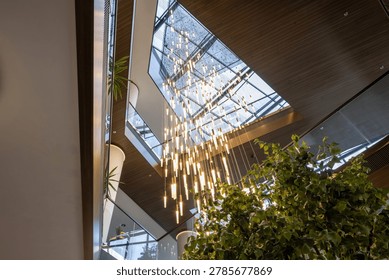 Stunning low angle view of massive modern chandelier and skylight glass roof