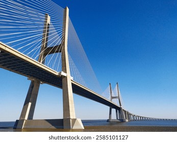 Stunning lowangle view of a cablestayed bridge against a vibrant blue sky.  Perfect for architecture, engineering, travel, and transportation projects.
