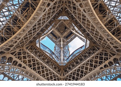 A stunning low-angle view of the Eiffel Tower in Paris captures its intricate iron lattice structure. This iconic landmark represents architectural brilliance and charm in the heart of Paris.