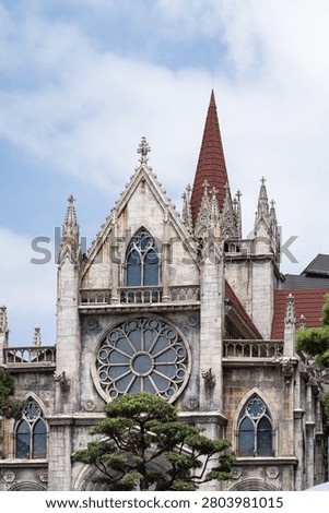 A stunning low-angle view of a Gothic-style stone cathedral, featuring intricate rose windows, pointed spires, and terracotta roofs, featured in image.