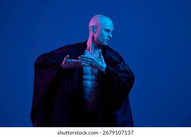 Stunning man in a dramatic pose, showcasing athleticism and grace in a black background with vibrant blue lighting, creating a captivating and stylish atmosphere.