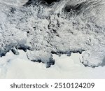 A stunning monochrome photograph captures a frozen landscape with snowcovered slopes, glacial landforms, and a winding stream. The icy scene is a testame. Elements of this image furnished by NASA