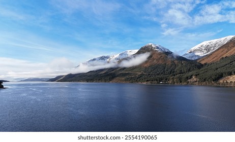 A stunning mountain landscape in Scotland, featuring a mix of snow-covered peaks and bare rock, with a tranquil lake reflecting the surrounding beauty. Ideal for nature and adventure lovers - Powered by Shutterstock