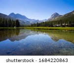 Stunning mountain range and pine forest reflected perfectly in a still lake.
