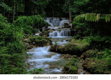 A stunning multitiered waterfall flows through a lush tropical jungle in kanchanaburi thailand creating a serene and tranquil wilderness environment.