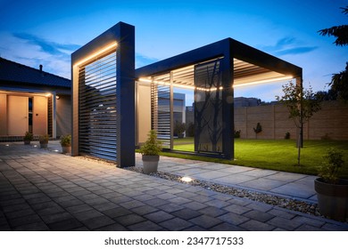 Stunning night photo of a luxurious outdoor pergola, boasting exquisite design with LED panels and lighting. Fully controllable via mobile, set in the garden of an upscale family home.