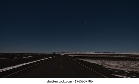 Stunning Night View Of Ring Road (route 1) With Diminishing Perspective In Southern Iceland Near Vatnajökull National Park In Winter Season With Snow-covered Mountains And Beautiful Clear Starry Sky.