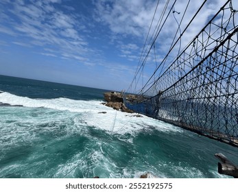 Stunning ocean view with a thrilling cable suspension bridge over crashing waves - Powered by Shutterstock