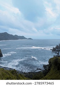 Stunning ocean wave patterns hitting the rocky shore of Menganti Beach in Kebumen, Indonesia