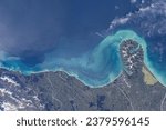 Stunning oceanfront where steep slopes meet turquoise shores. Satellite image of currents continuing along the coast with clouds.  Elements of this image furnished by NASA.