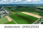 A stunning overhead shot that contrasts the structured urbanity of a small town against the lush, sprawling farmland that surrounds it.