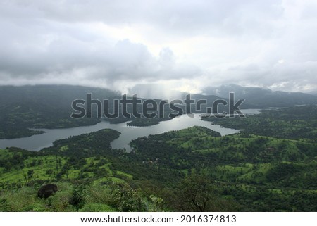 Stunning panoramic landscape view of beautiful Koyna river surrouded by lush green scenery from the top of a mountain during monsoon in Mahabaleshwar, Maharashtra, India.