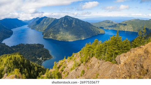 A stunning panoramic view captures the pristine Lake Crescent stretching out below, seen from the summit of the popular Mount Storm King Trail in Olympic National Park, Washington State.