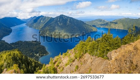 A stunning panoramic view captures the pristine Lake Crescent stretching out below, seen from the summit of the popular Mount Storm King Trail in Olympic National Park, Washington State.