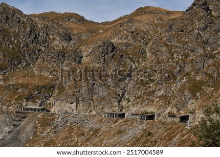 Stunning panoramic view of mountain pass with a series of tunnels carved into the rugged terrain.Natural beauty of landscape is juxtaposed with the engineering marvel of the tunnels. Transfăgărășan.