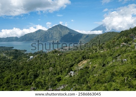 Stunning panoramic view of a tranquil lake nestled in a lush valley, surrounded by majestic mountains under a vibrant blue sky. 
