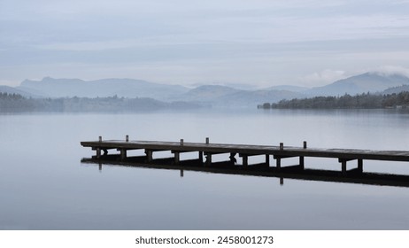 Stunning peaceful landscape image of misty Spring morning over Windermere in Lake District with boats moored on lake and distant misty peaks - Powered by Shutterstock
