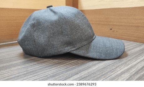 A stunning photo featuring a baseball cap is beautifully placed on a wooden table. This nicely positioned hat features a trendy design and high quality. Soft light plays an important role in highlight
