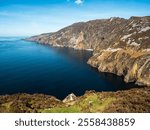 Stunning picturesque view on Slieve league cliffs, county Donegal, Ireland. Warm sunny day. Irish landscape scene. Blue cloudy sky and ocean surface, rough and tall cliffs.