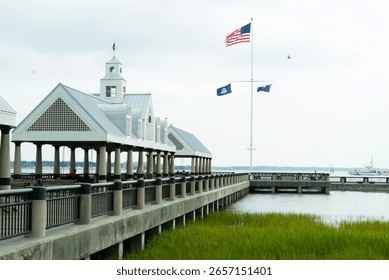 A stunning pier showcases America’s flags while providing a view of peaceful waters and abundant marshlands, embodying the essence of summer leisure and nature’s wonders.