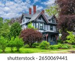 Stunning Queen Anne Victorian home with red trim and lush landscape in Newton, Massachusetts, USA