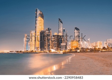 Stunning sandy beach near Corniche seaside embankment with great night view of Abu Dhabi, UAE towering skyscrapers