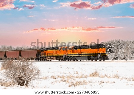Stunning scene of a freight train in winter with sunrise in background in northwestern Montana