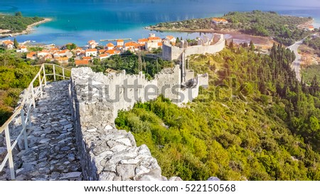 Stunning scenery panoramic view of the village of Ston in Dalmatia, Croatia. There is big wall of white stone in the foreground and houses with red roofs, mountain and blue sea in the background