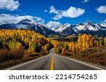 Stunning scenic fall drive along Colorado 145 near Telluride Colorado on a sunny afternoon with yellow Aspen trees near peak fall colors, and 2 lane highway in the foreground