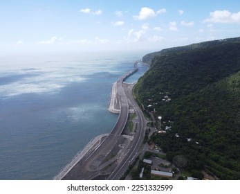 A stunning shot of the new Route du Littoral on La Réunion island. The camera captures the panoramic view of the road, with the beautiful blue ocean on one side and the lush green vegetation on the ot - Shutterstock ID 2251332599