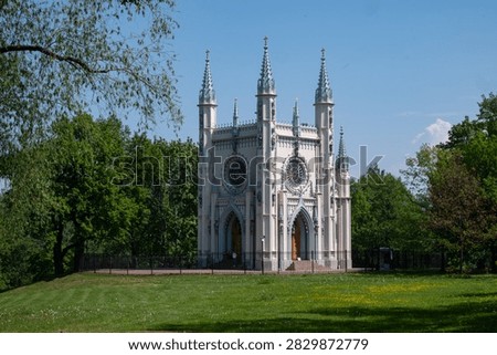 Stunning spring landscape view of the neogothic Gothic Chapel architecture building on a green lawn with blooming flowers in Alexandria Park of Peterhof