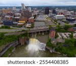 A stunning stock photo capturing the dynamic skyline of Rochester, NY, with the majestic High Falls in the foreground. The image showcases the blend of natural beauty and modern urban architecture.