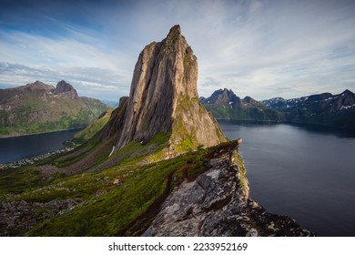 Stunning summer landscape from Mount Hesten on Iconic Mountain Segla in late evening light. Clear fjord waters and mountain range in background, Fjordgard, Senja, Norway