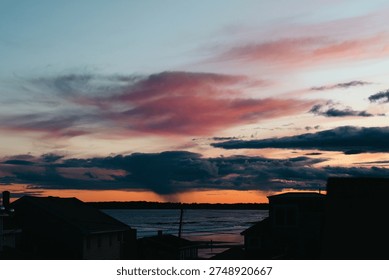 A stunning sunset with dramatic cloud formations painting the sky in vivid colors, creating a striking contrast against the calm waters in a beautiful coastal setting.
