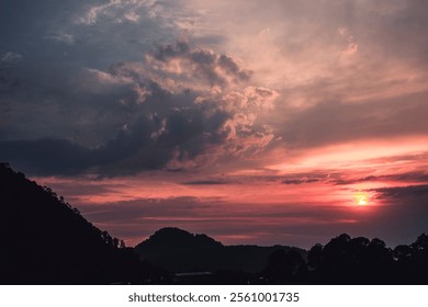 Stunning sunset in dynamic clouds over a silhouetted  hillside.