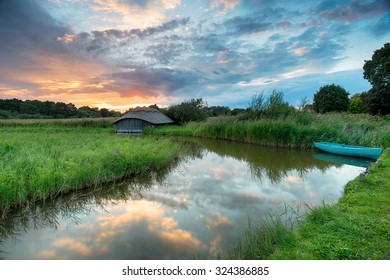 Stunning Sunset Over A Boat And Thatched Boat House In Reeds On The Norfolk Broads