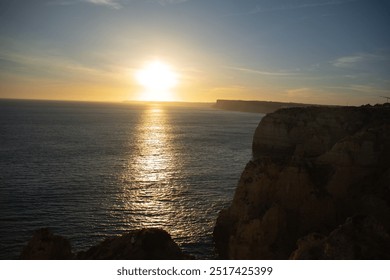 A stunning sunset over a calm ocean near Algarve’s rocky coastline. - Powered by Shutterstock