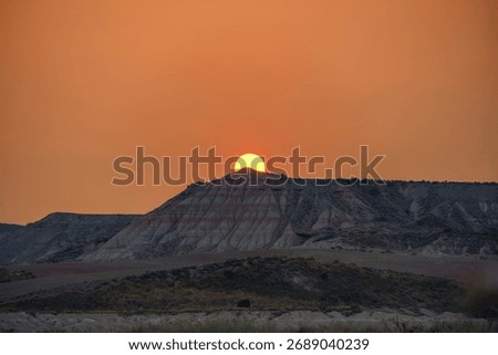 Stunning sunset over eroded mesa formation in Bardenas Reales semi-desert landscape, Navarra, Spain. Dramatic silhouette with warm sky. Ideal for travel.