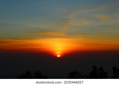 Stunning sunset over the horizon, featuring a radiant orange sun dipping below the clouds and casting vibrant hues across the sky. The deep gradient of warm colors, from gold to crimson, creates a mes - Powered by Shutterstock