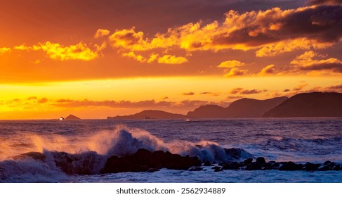 A stunning sunset over the ocean, with vibrant orange and yellow hues illuminating the sky. Waves crash against rocky shores, while distant islands are silhouetted against the colorful backdrop. - Powered by Shutterstock