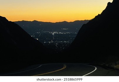 Stunning sunset view from Little Cottonwood Canyon in Salt Lake City, capturing city lights in the distance, a winding mountain road, and the canyon's silhouette against a glowing sunset sky - Powered by Shutterstock