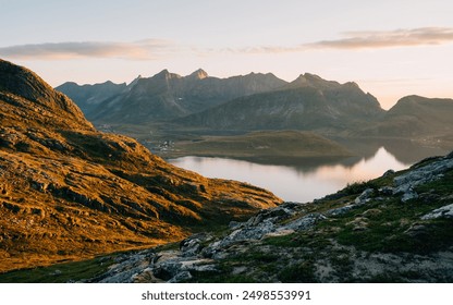 Stunning sunset view from a rocky hilltop in the Lofoten Islands, Norway, showcasing the serene landscape with a picturesque blend of mountains, valleys, and a calm body of water reflecting the colorf - Powered by Shutterstock